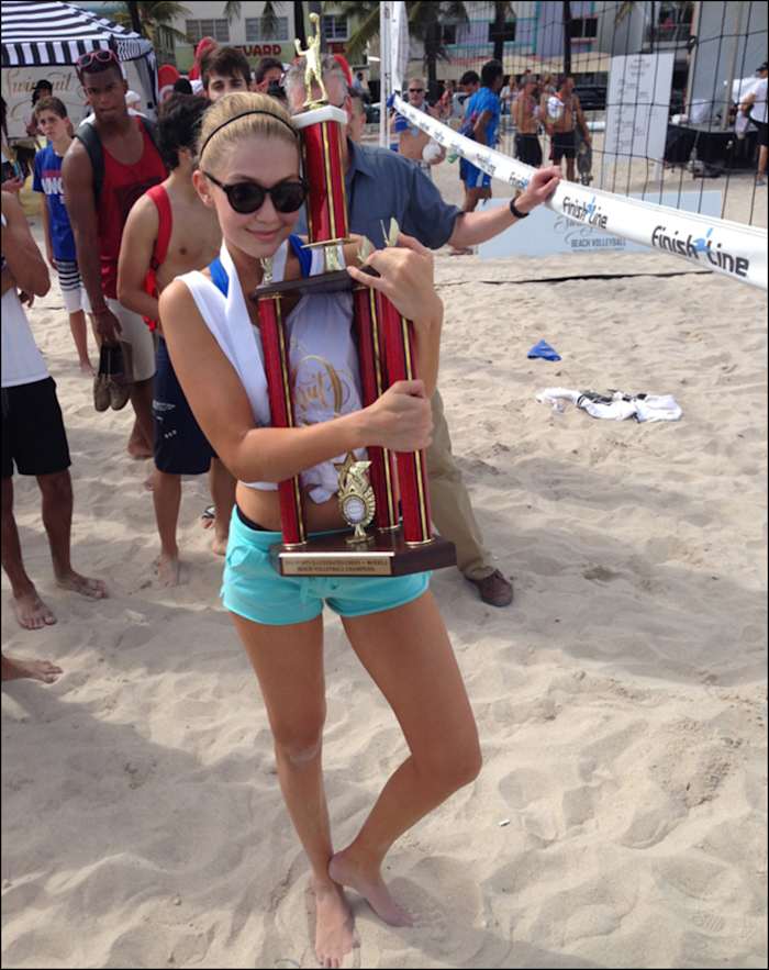 Gigi, who kept her junior Olympic volleyball experience under wraps during the models vs. celebrity chefs volleyball tournament, clings to her team's trophy. The unwieldy prize went home with Gigi to NYC, warranting its own seat on the charter flight.